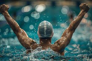 A man in a swim cap is in the water, splashing and celebrating photo