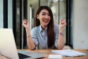 Joyful businesswoman sitting at desk looking at laptop screen talking with friend make informal call photo