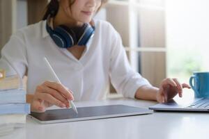 Fashion designer using tablet and sketches while working at table in studio. photo