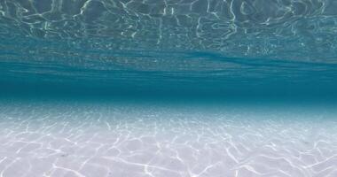 Blue ocean underwater with white sandy bottom and waves. Sea texture video