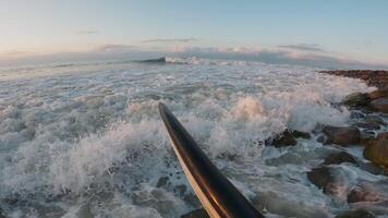 surfeur avec une première personne vue aller à le océan avec une planche de surf. s'écraser vagues à le coucher du soleil ou lever du soleil video