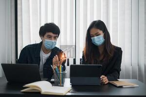 Businessman and team wear mask and try to explain about his work at home office. Work from home concept. photo