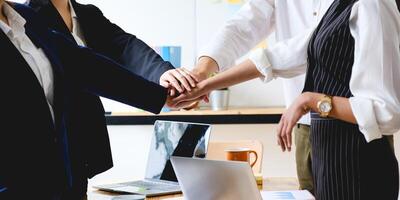 As they laugh and celebrate their performance, the business team makes a handshake motion. photo