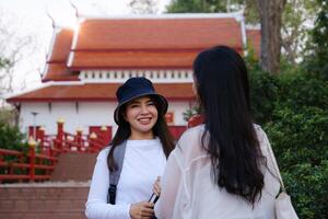 Asian woman traveler with backpack using maps on tablet and sitting in park, travel holiday relaxation concept photo