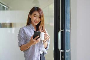 Young beautiful woman holding coffee cup and feeling fresh while sitting at her working place at monday morning. photo