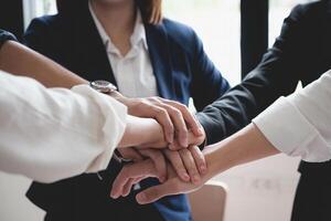 Business team putting their hands together gesture as they laugh and cheer their success. Achievement and Business Goal Success Concept. photo