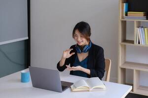 Happy young asian business woman with headphone to greeting or presentation to partner during making conference with her team. photo