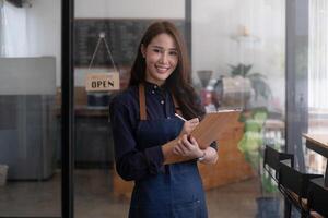 retrato de un hermosa barista con tableta a su cafetería. pequeño negocio propietario concepto. foto