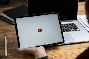 CHIANGMAI THAILAND - AUG 02, 2021 . Woman holding Apple iPad with Youtube logo on the screen on wooden desk photo