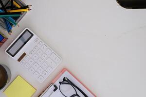 Modern white wooden desk table calculator and business tools office. top view photo