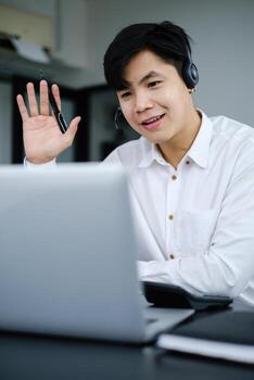 Businessman discuss with partners by call. Male technical support agent trying to explain something to a client while working on laptop at call center. photo