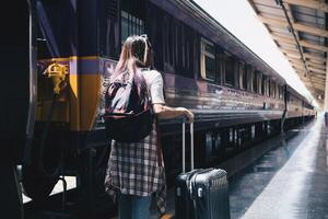 Image of a woman with a rucksack standing at a train station waiting to board a train. concept of solo travel photo
