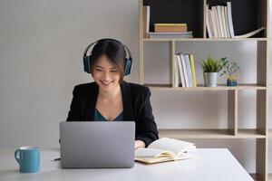 A joyful woman with headphones concentrates on a webinar on her laptop computer. photo