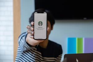 Chiang Mai, Thailand . Mar 19 2021 . Asian man showing Starbucks logo on iPhone screen in Starbucks coffee shop photo