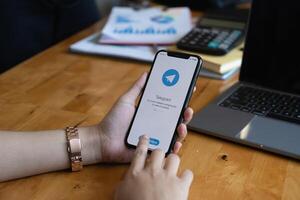 CHIANG MAI, THAILAND, MAR 19, 2021 . Woman hand holding iPhone X with social networking service Telegram on the screen. iPhone 10 was created and developed by the Apple inc. photo