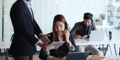 Female operator discussing with her team before communicates with the client. photo