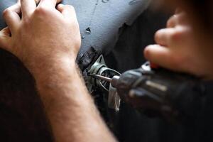 cordless screwdriver that wraps a screw into a hole in a sofa close up photo