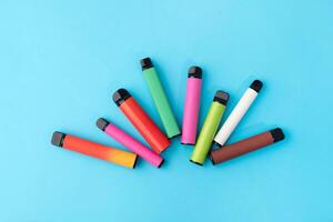 colorful disposable electronic cigarettes on a blue background. The concept of modern smoking photo