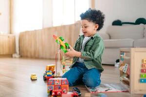 Concentrated latinos boy playing toys sitting on warm floor in modern living room. Baby development. Small tower. Learning creative concept photo