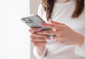 Kyiv, Ukraine. April 25, 2024. Woman using a new mobile phone, iphone 15 smartphone close-up, holding cellphone in hands. texting message, scrolling photo