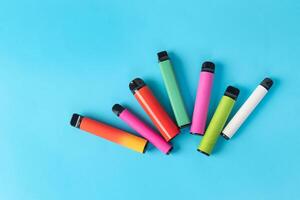 colorful disposable electronic cigarettes on a blue background. The concept of modern smoking photo