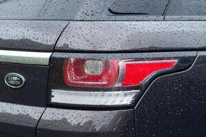 Kyiv, Ukraine - April, 2024. Land Rover Discovery Sport modern gray car with water drops. Body, Taillight close-up photo