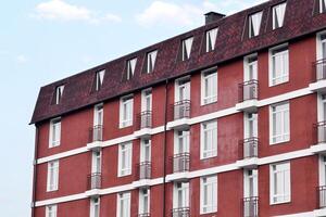 edificio un nuevo casa , el marrón fachada de el edificio con balcones en contra azul cielo foto