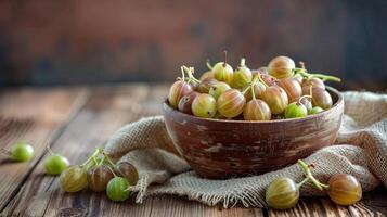 Ripe gooseberries fruit in bowl with sackcloth on wood table photo