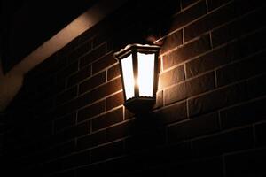 Retro-style lamp hangs on a red brick wall at night, copy space. photo