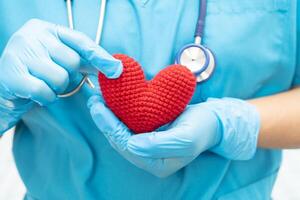 médico sosteniendo un corazón rojo en la sala del hospital, concepto médico fuerte y saludable. foto