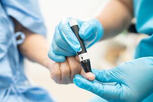 Doctor check diabetes from finger blood sugar level with finger lancet. photo