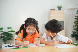 Two children are sitting at a table, drawing and smiling. Concept of joy and creativity, as the children are engaged in a fun activity together photo