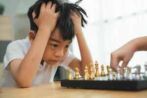 un chico es jugando ajedrez con otro persona. él es mirando a el tablero con un triste expresión foto