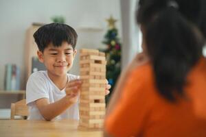 un chico es jugando con un de madera bloquear torre mientras un niña relojes. el chico es sonriente y parece a ser disfrutando él mismo foto