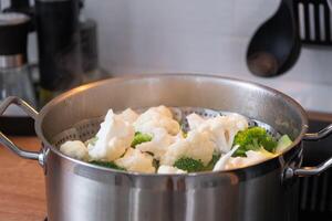 brócoli y coliflor son al vapor en un cacerola - sano dieta, bebé alimento, Cocinando en un buque de vapor foto