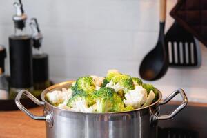 brócoli y coliflor son al vapor en un cacerola - sano dieta, bebé alimento, Cocinando en un buque de vapor foto