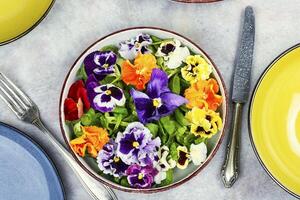 Salad decorated of edible flowers, vegetarian food. photo