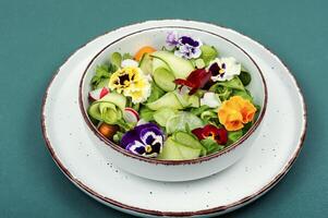 Salad of vegetables and flowers in a bowl. photo