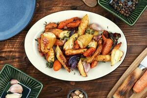 Baked parsnip root and carrots on a wooden table. photo