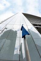 The flag of the European Union is reflected in the glass of a skyscraper. The flag of the European Union on the background of a building under construction, photo