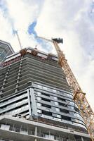 Construction of a multi-storey building. A view from below of a skyscraper under construction. Glazing of the facade of the building. Construction of a new multi-storey building. photo