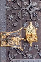 Door decorations. Gold hardware elements. vintage weathered rustic oak door. decorative black wrought and forged iron mounting. forged iron surface decoration. old architecture concept. photo