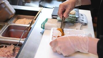 chef maken sushi sashimi nigiri. meester klas. professioneel chef is tonen hoe naar maken sushi. Japans voedsel voorbereidingen treffen werkwijze. Holding voedsel in handen video