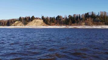 Landscape with a river. Clip. A spring frozen river with a view of which you can see frozen forests and grass and a bright morning sky. video