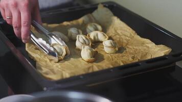 Dumplings cuit sur une poêle. art. le cuisinier a pris un boulette avec pinces. huit cuit Dumplings mensonge sur une cuisson feuille et papier video