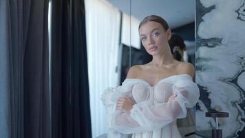 hermosa elegante novia durante sesión de fotos adentro. acción. yong mujer en un blanco vestir con corsé posando en frente de el cámara. video