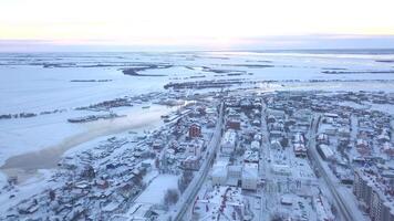 Top view of town on background of fields in winter. Clip. Beautiful winter landscape of town with white fields on cloudy day. Snowy white fields and town video