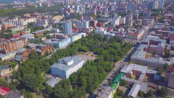 City view from a helicopter. Clip. Large houses standing next to each other next to a park area and large green trees and a road nearby. video