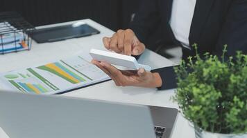 Close up Business woman using calculator and laptop for do math finance on wooden desk, tax, accounting, statistics and analytical research concept video