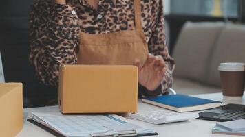 opstarten klein bedrijf ondernemer van freelance Aziatisch vrouw gebruik makend van een laptop met doos vrolijk succes online afzet verpakking doos en levering mkb idee concept video